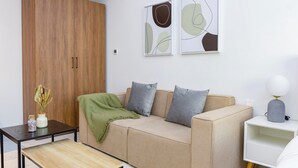 A modern living room with a beige sofa, a wooden wardrobe, and abstract wall art.
