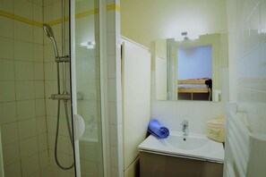 Un bagno con doccia, lavandino e specchio.