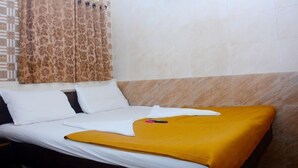 Una habitación de hotel con una cama, almohadas blancas, un edredón amarillo y una cortina estampada.