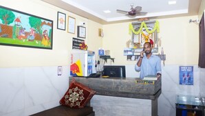 Una zona de recepción con mostrador, ventilador de techo, certificados enmarcados y un mural colorido en la pared.