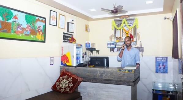 A reception area with a counter, a ceiling fan, framed certificates, and a colorful mural on the wall.
