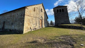 A stone building with a bell tower, a wooden door, and a bench in front.