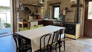 A kitchen with a dining table, chairs, a stove, and a washing machine.