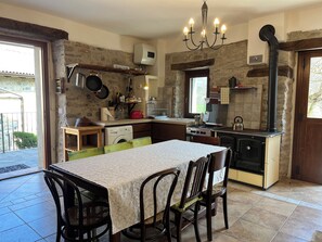 A kitchen with a dining table, chairs, a stove, and a washing machine.