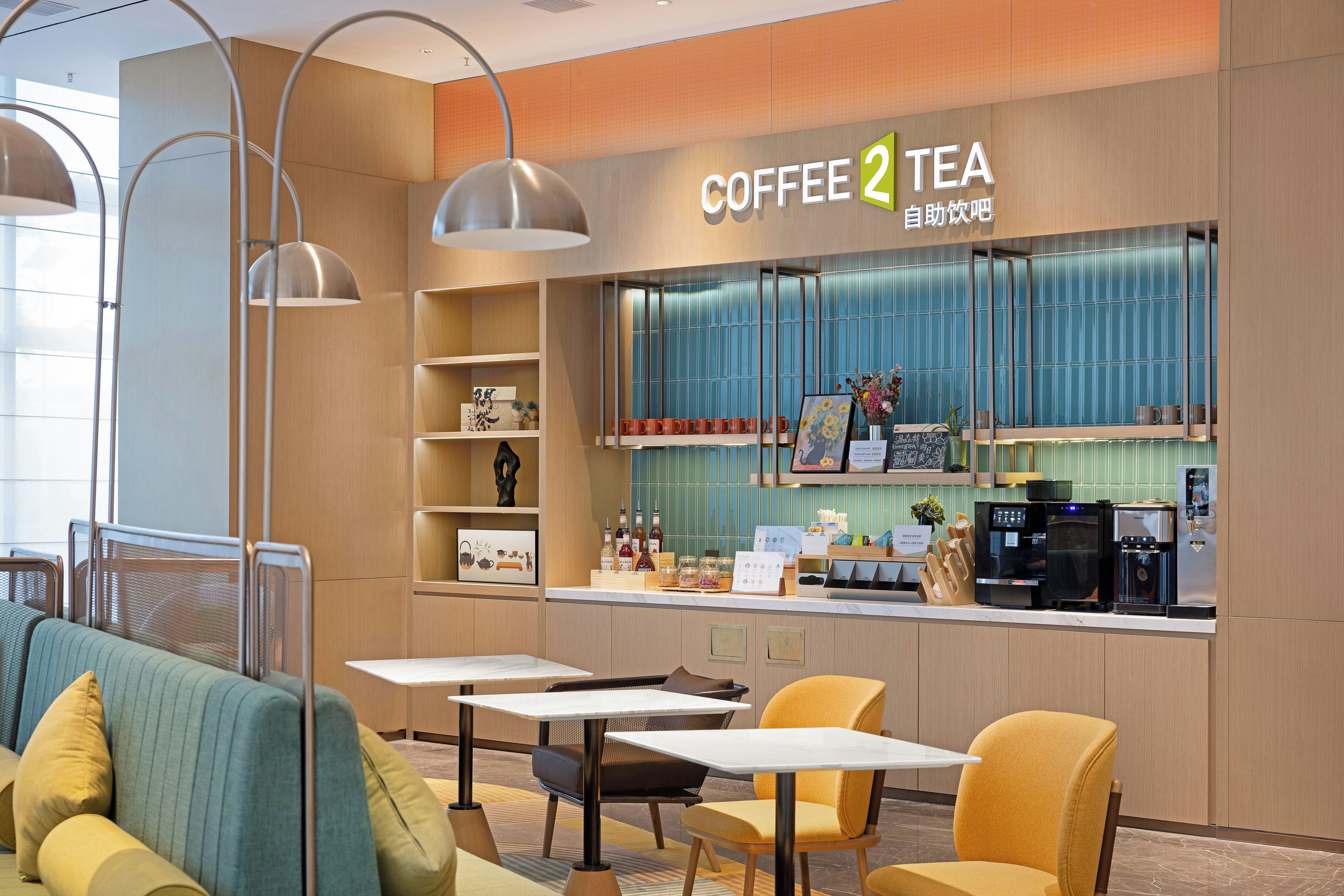A coffee shop interior with seating, a counter with coffee machines, and shelves with various items.