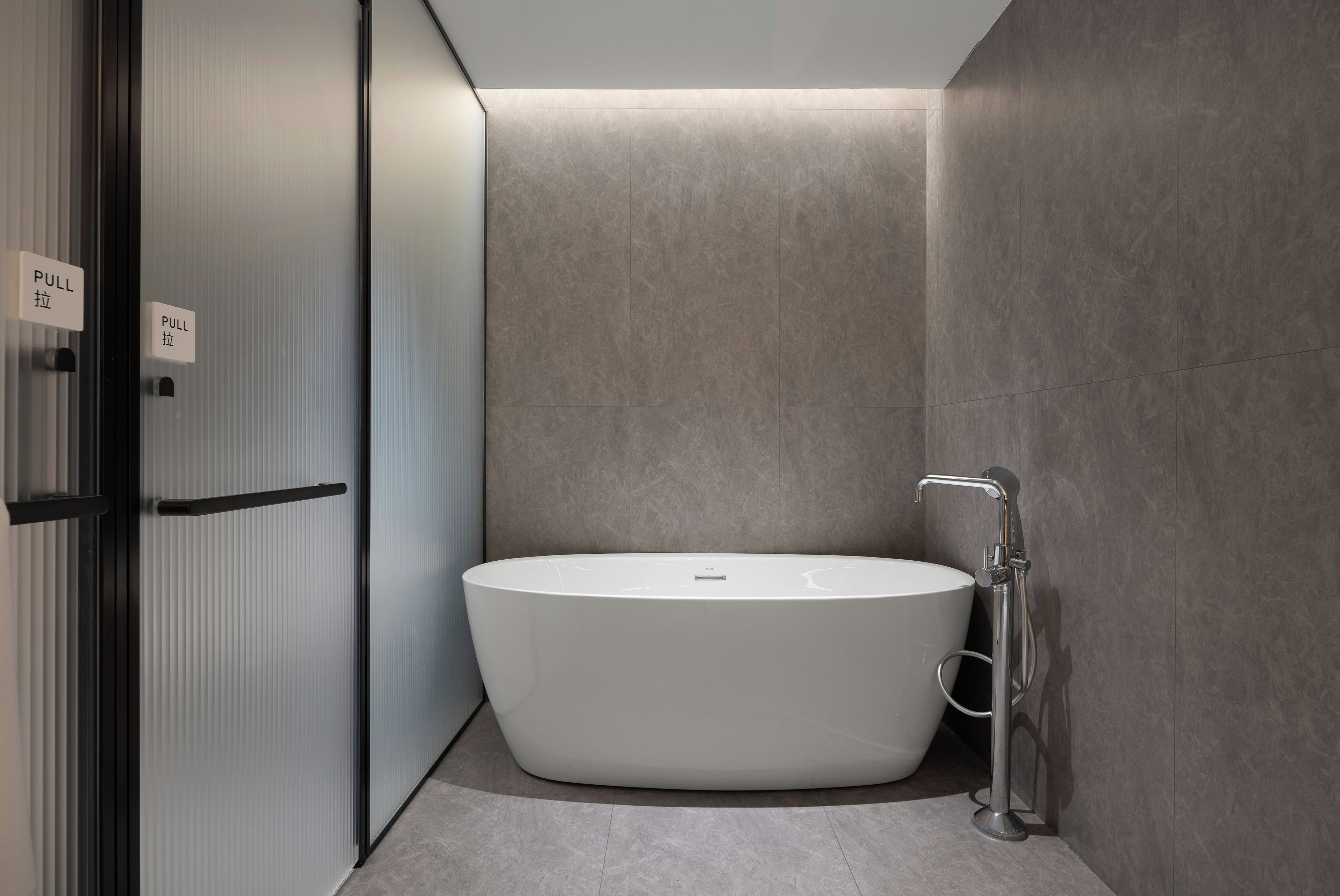 Une salle de bain moderne avec une baignoire sur pieds, un porte-serviettes et un distributeur de serviettes fixé au mur.