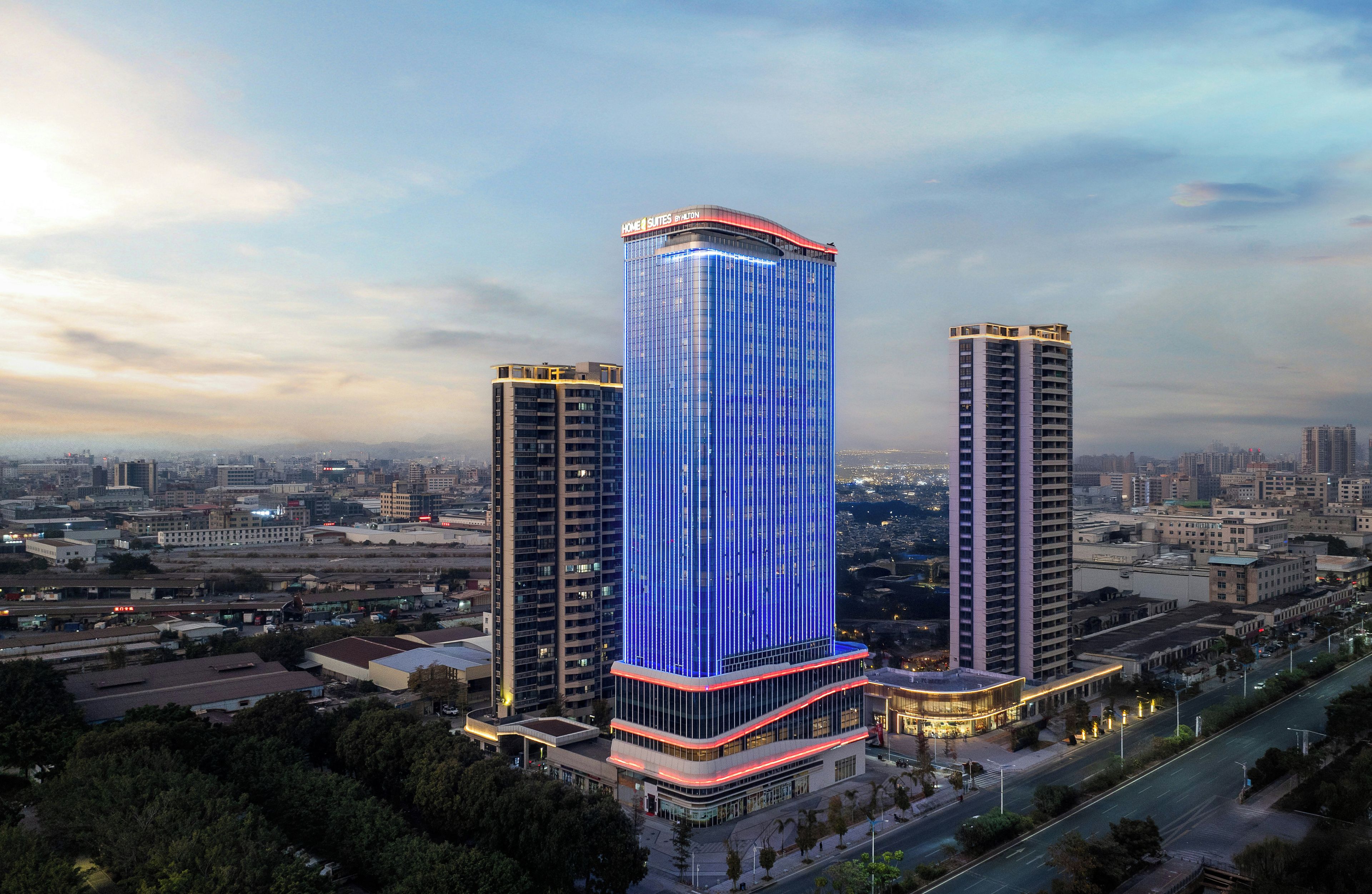 A high-rise hotel with a prominent vertical light display, surrounded by a cityscape.