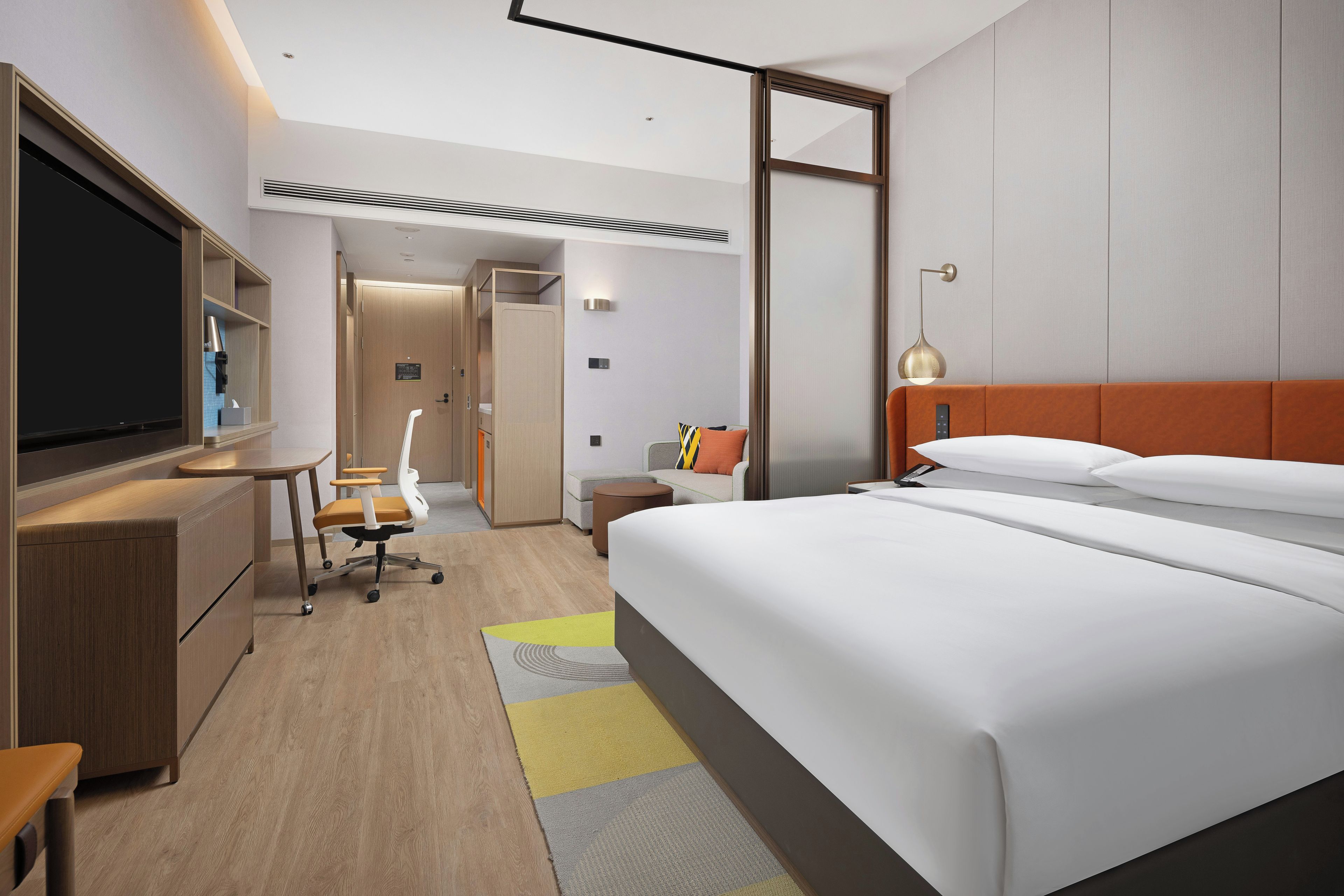 Una habitación de hotel moderna con una cama grande, un escritorio, un televisor y un baño.