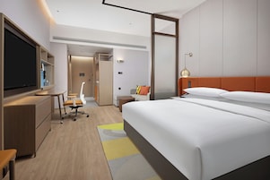 Una habitación de hotel moderna con una cama grande, un escritorio, un televisor y un baño.