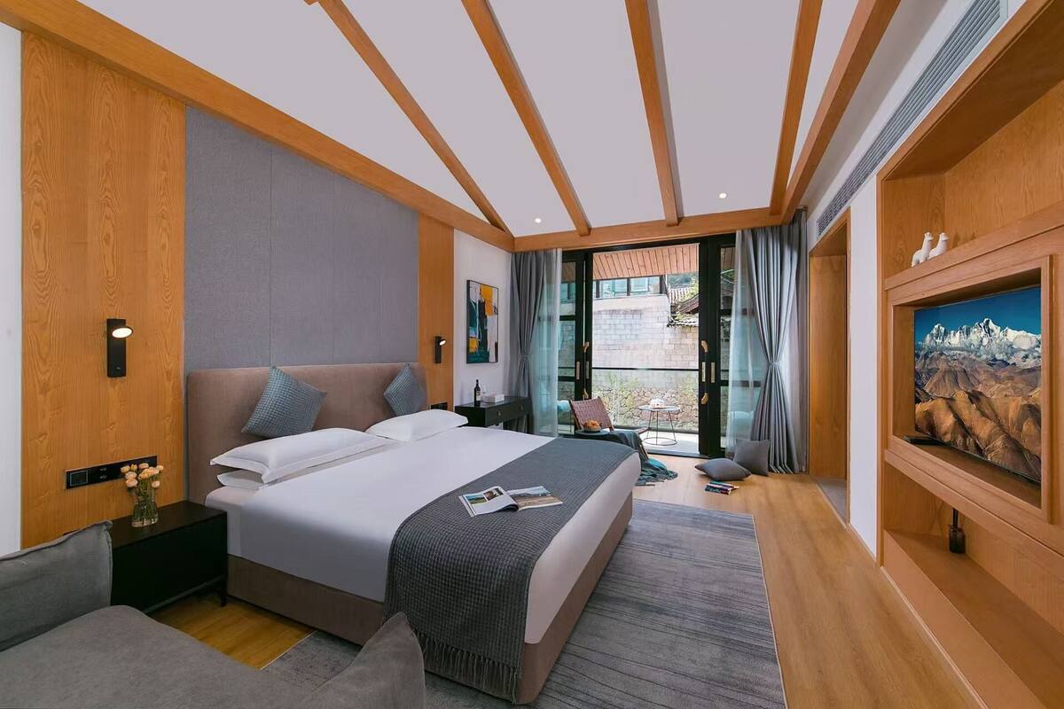 A modern hotel room with a large bed, a desk, a chair, and a painting on the wall.