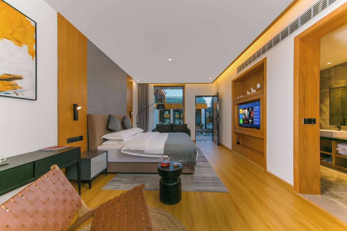 A modern bedroom with a large bed, bedside tables, a desk, and a TV.