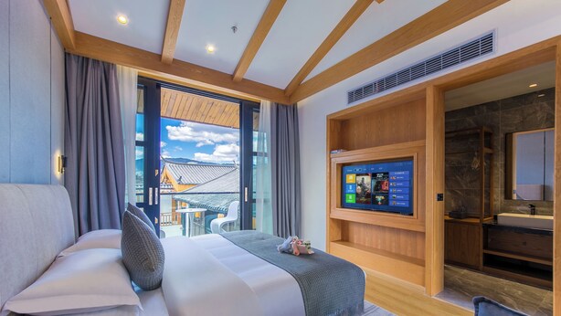 Ett modernt hotellrum med en stor säng, en tv som är monterad på väggen och utsikt över omgivningarna.