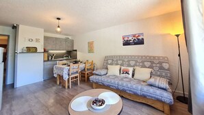 Una sala de estar acogedora con sofá, mesa de comedor y zona de cocina.