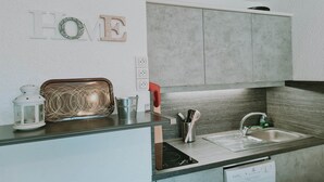 Una cocina moderna con lavavajillas integrado, un lavabo de acero inoxidable y una encimera con una tetera y una bandeja decorativa.
