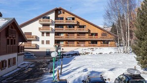 A multi-story hotel with wooden balconies and a ski slope in the background.
