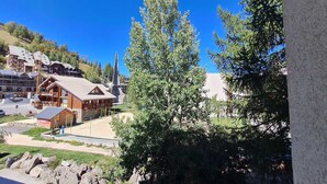A lodge with a wooden exterior, a ski lift in the background, and a clear blue sky.