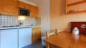 A compact kitchen with wooden cabinets, a microwave, a coffee maker, and a dishwasher. - Alpine Retreat with Balcony (Les Deux Alpes)