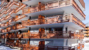 A multi-story hotel with balconies, large windows, and a snow-covered ground. - Alpine Retreat with Balcony (Les Deux Alpes)