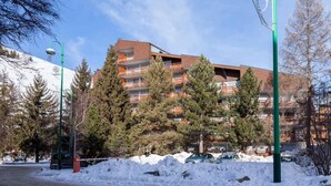 A multi-story building with balconies, surrounded by snow and trees. - Alpine Retreat with Balcony (Les Deux Alpes)