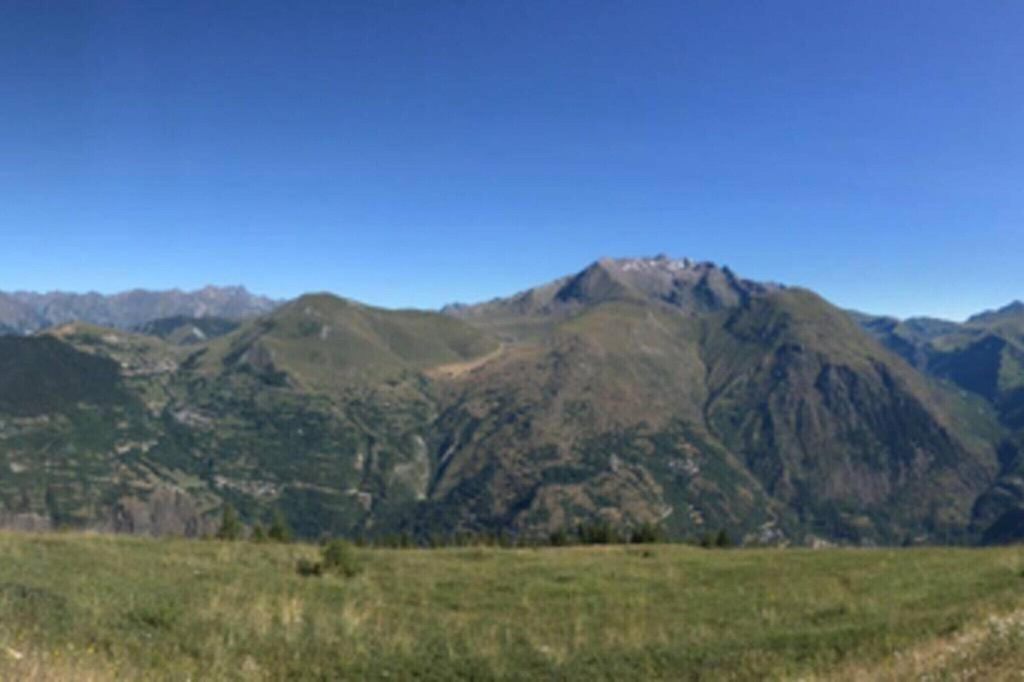 A mountainous landscape with a prominent peak and a clear sky.