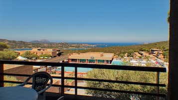 Ein Balkon mit Blick auf eine Küstenlandschaft, einschließlich Gebäude und einem Pool.