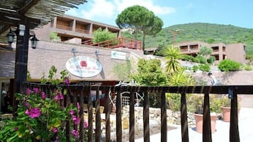 Ein Restaurant mit Außenbereich, einer Stein-Fassade und Blick auf eine Hügellandschaft.
