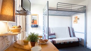 Ein Schlafraum mit Etagenbetten, einem Fernseher, einem Tisch mit Frühstücksangeboten und einem Fenster mit Vorhängen.