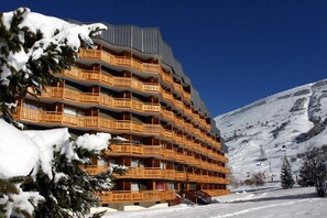 A multi-story hotel with balconies, surrounded by snow-covered mountains.