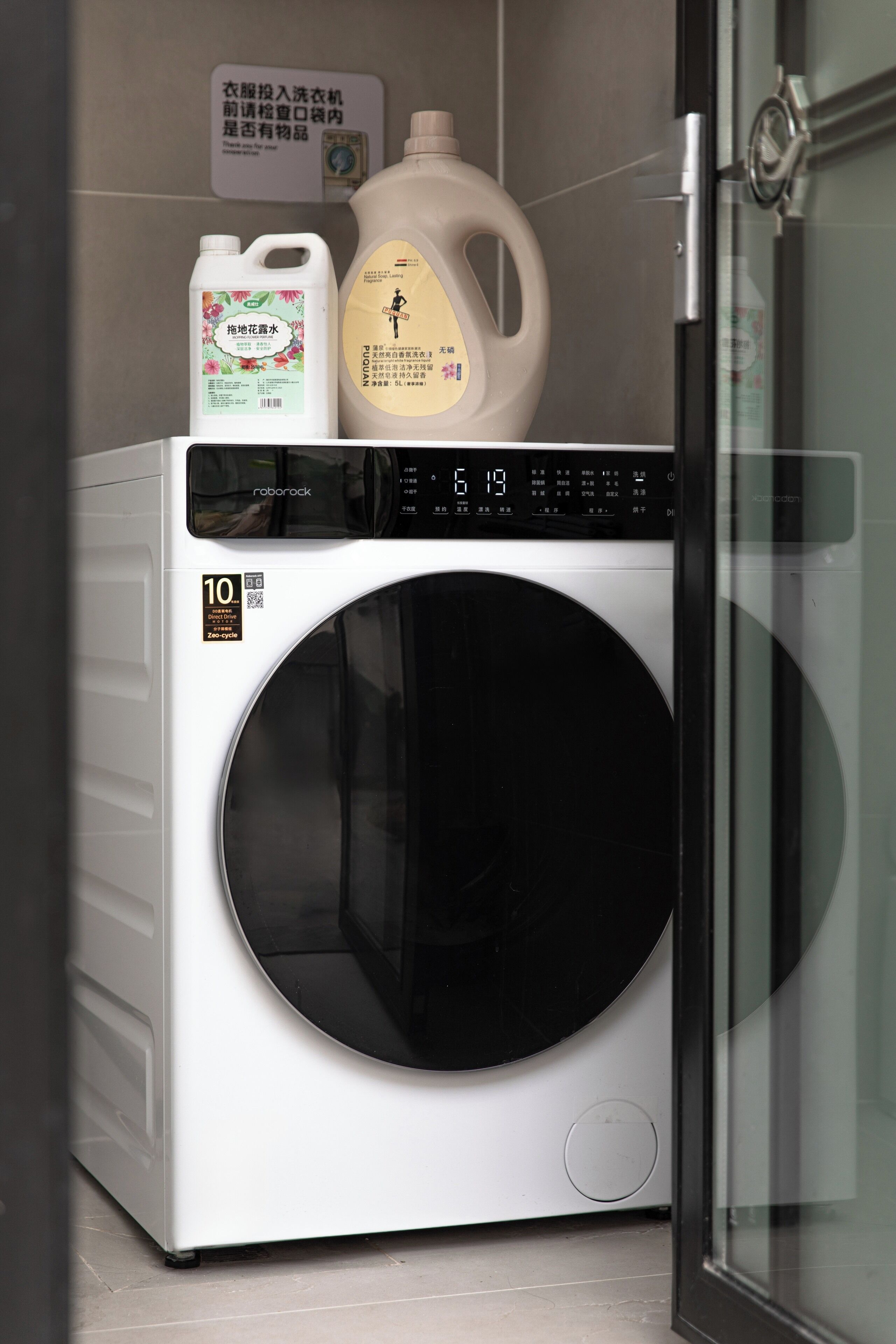A front-loading washing machine with a digital display and a QR code sticker.