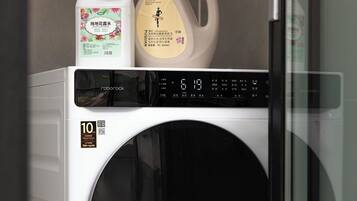 A front-loading washing machine with a digital display and a QR code sticker.