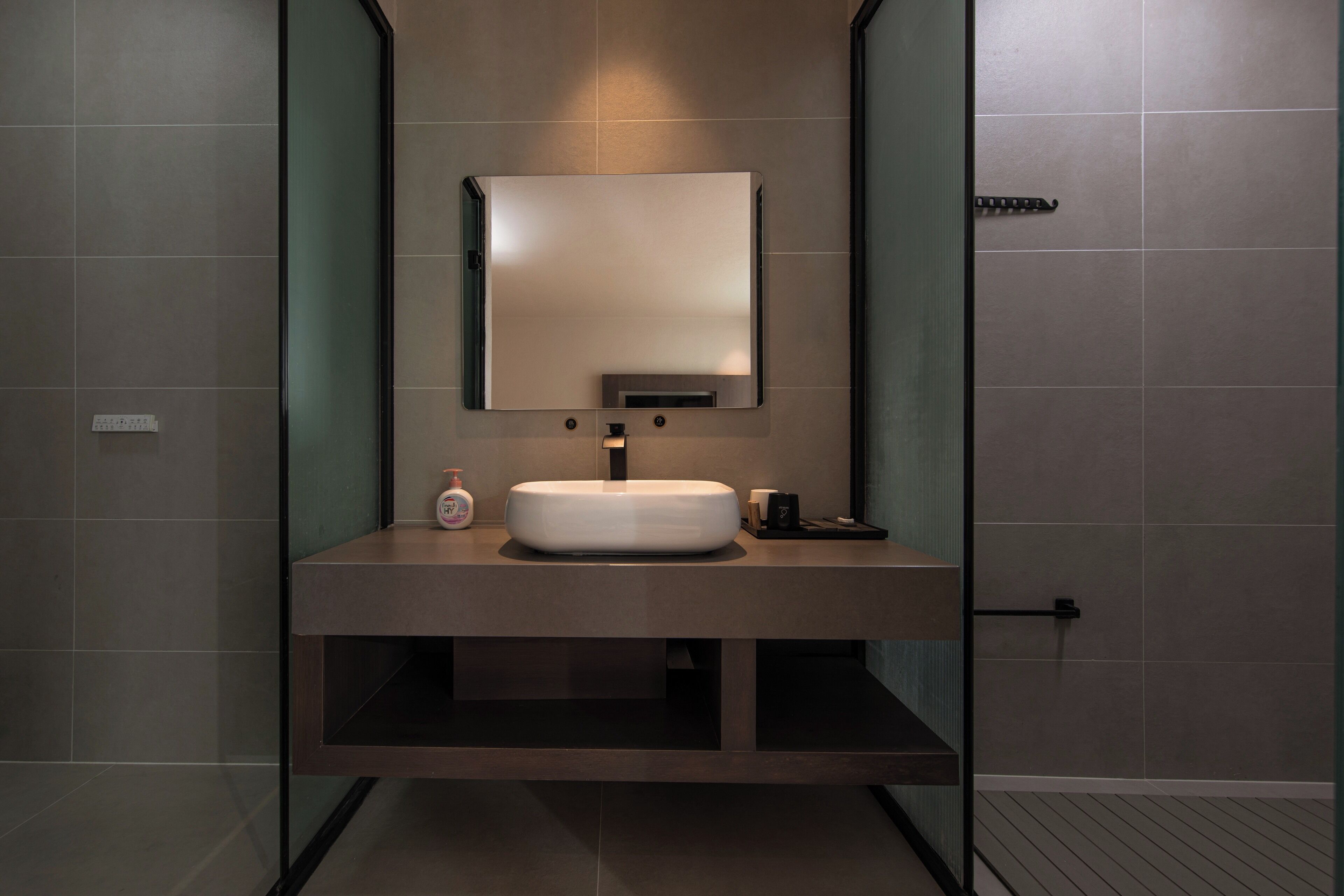 Un baño moderno con un espejo grande, un lavamanos redondo y un perchero para toallas.