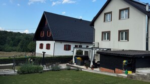 A two-story house with a sloped roof, a covered patio area, and a well-maintained lawn. - Millenium House (Plitvicka Jezera)