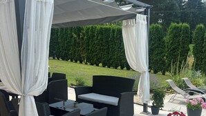 An outdoor patio with wicker furniture and a canopy. - Millenium House (Plitvicka Jezera)