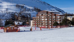 Une station de ski dotée d’un grand bâtiment, de remontées mécaniques et offrant une vue sur une montagne enneigée.