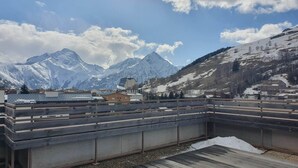 Une terrasse sur le toit offrant une vue sur des montagnes enneigées et un ciel dégagé.