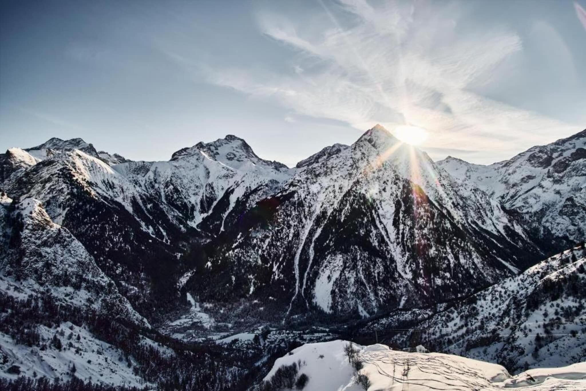 Un paysage montagneux aux sommets enneigés, sous un ciel dégagé.