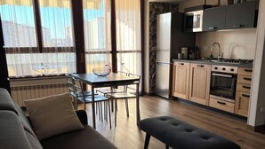 Una sala de estar moderna con sofá, una mesa de comedor con sillas y una zona de cocina con electrodomésticos.