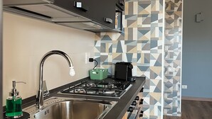 Una cocina moderna con un lavamanos de acero inoxidable, una estufa a gas y una máquina de café.