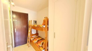 A bunk bed with a colorful mattress, a wooden ladder, and a door in the background. - Ski on rue du Grand Plan (Les Deux Alpes)