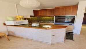 A compact kitchen with a central island, built-in microwave, oven, and a backsplash with green tiles. - Ski on rue du Grand Plan (Les Deux Alpes)