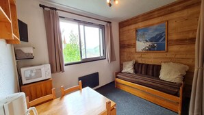 Una habitación acogedora con un banco de madera, una mesa, un microondas y un cuadro en la pared.