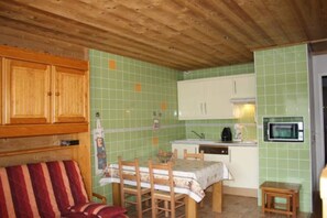 Compact kitchen area with a dining table and chairs, microwave, and kitchen counter.