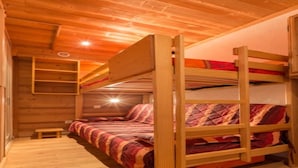 Ein Schlafzimmer mit Etagenbetten, Holzwänden und einer geneigten Decke.