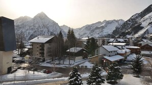 Eine verschneite Stadt mit Häusern und einem markanten Berggipfel im Hintergrund.