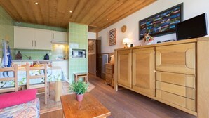 Eine gemütliche Küche mit Holzausstattung, einem Essbereich mit einer Bank und einem an der Wand montierten Fernseher.