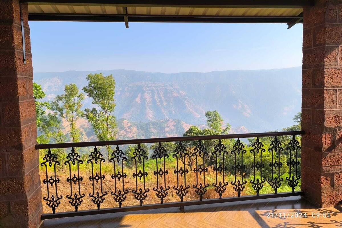 A balcony with a wrought iron railing, a brick wall, and a view of a canyon landscape.