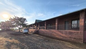 A brick building with a porch and a car parked in front. - Eagle Eye Resort (Mahabaleshwar)