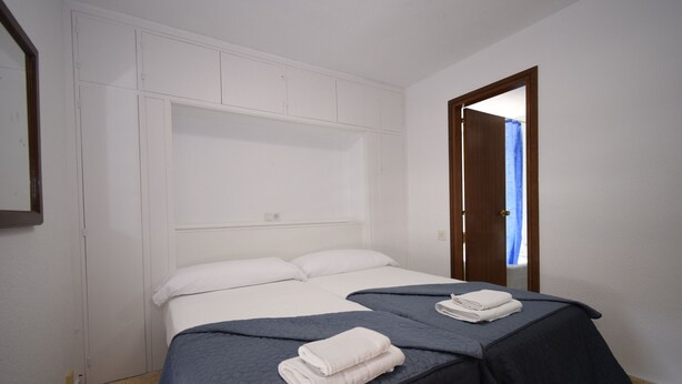 Une chambre à coucher avec deux lits, des têtes de lit blanches et une porte en bois.