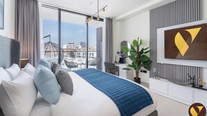 A modern hotel room with a large bed, a desk, and a view of the cityscape. - Vogue | Binghatti Galaxy JVC near Circle Mall (Dubai)