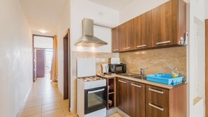 A modern kitchen with wooden cabinets, a gas stove, a microwave, and a sink. - Seashells Apartment with Sea View Terrace (Bugibba,)